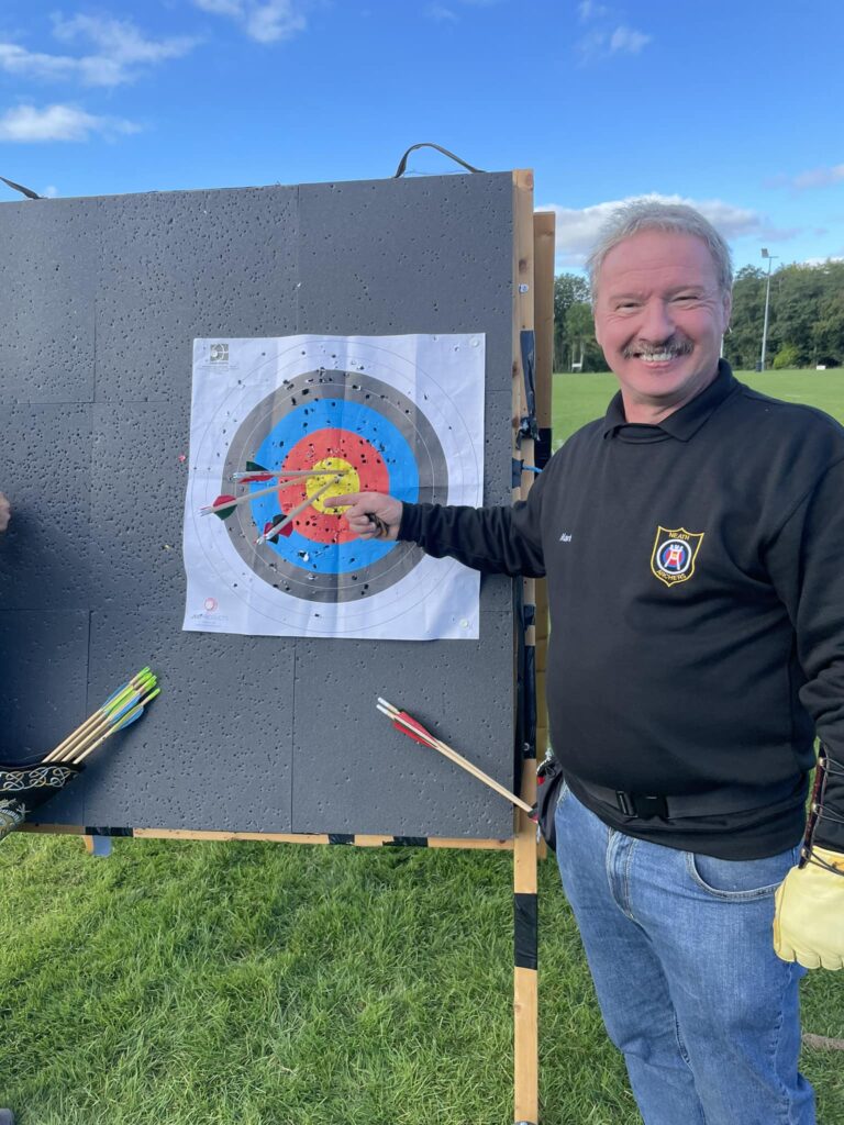 a member of neath archers' pointing at 3 arrows in the gold